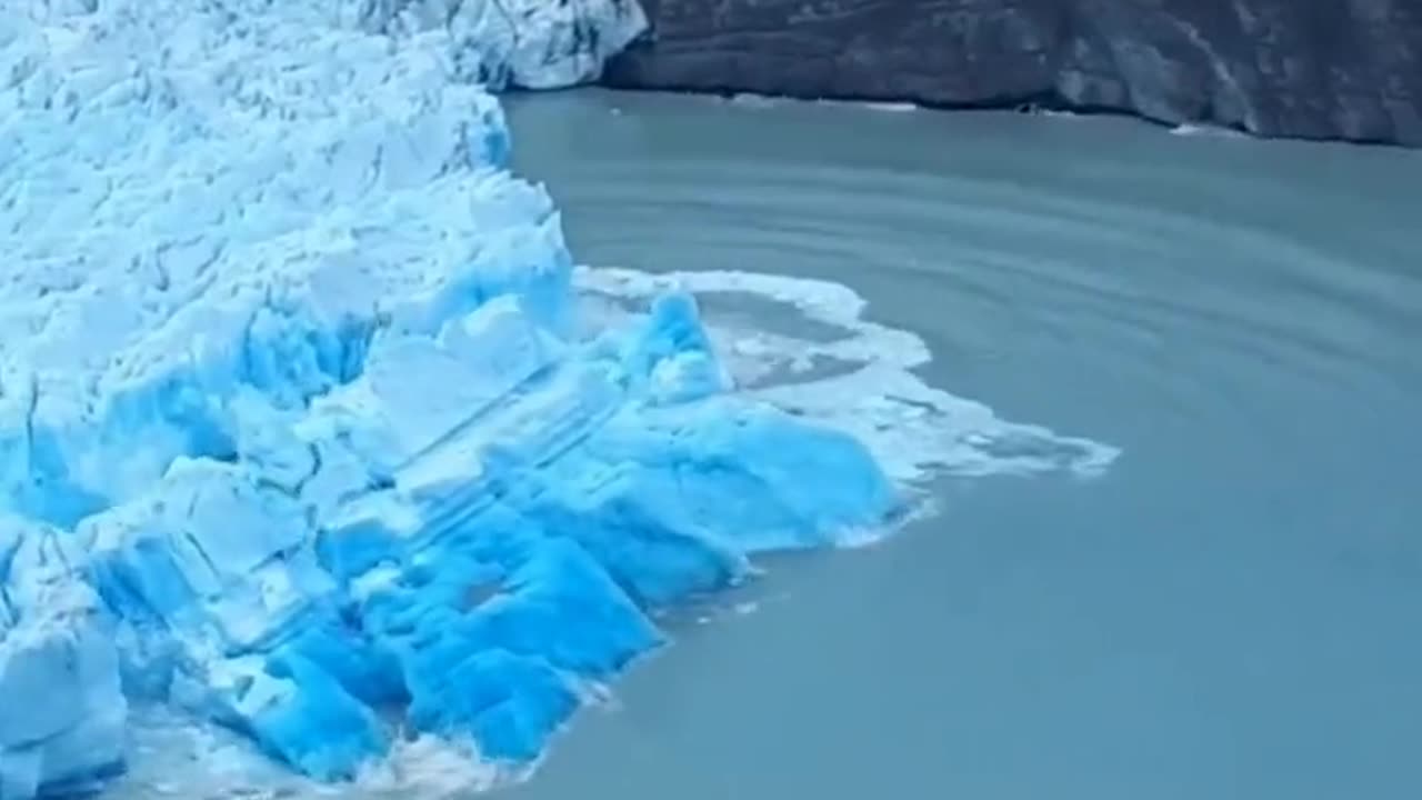 Rare sighting of the deep blue underside of a glacier during a collapse caused by glacier calving