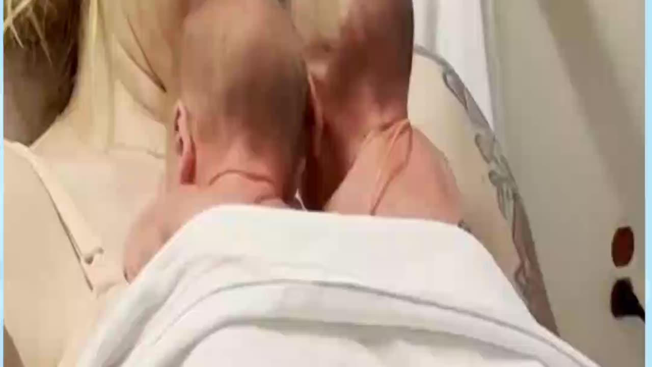 A newborn baby stretched his arm out for a cuddle with his twin