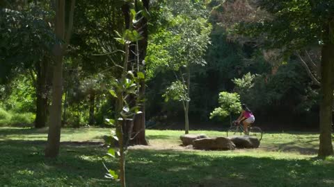 A woman riding her bicycle at a green park