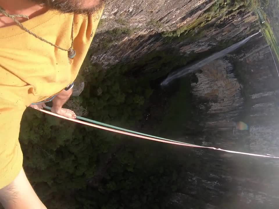Guy Highline Crossing While Overlooking a Beautiful Waterfall