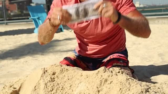 A Man Digging Money From The Sand