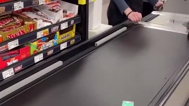 Cashier is waiting on tic tacs to go all the way down the conveyor belt