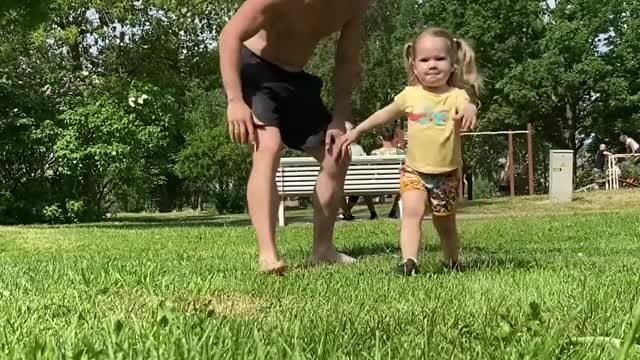 Little Girl Performs Various Exercises With Father In Park