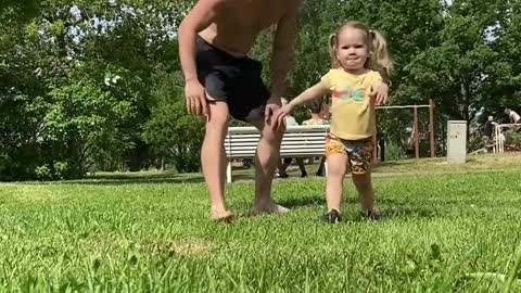 Little Girl Performs Various Exercises With Father In Park