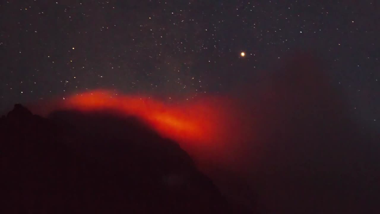 Active volcano smoking during the starry night