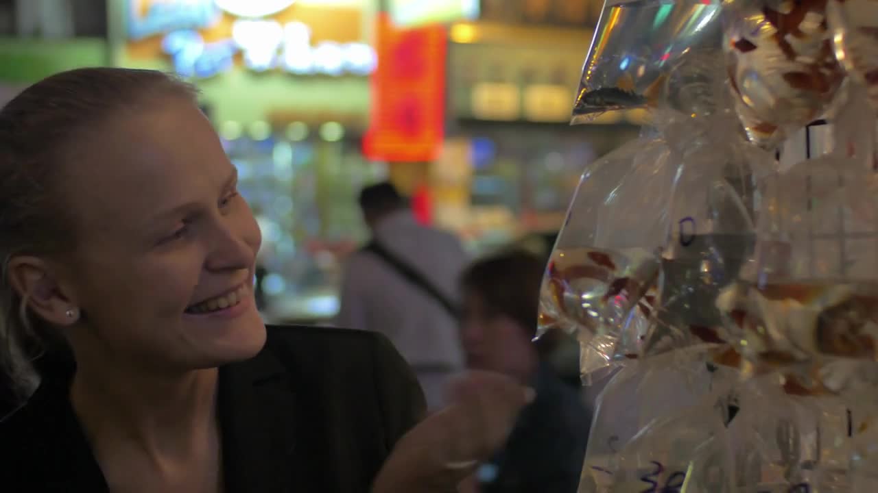 Woman looking at goldfish in plastic bags sold in street market of Hong Kong