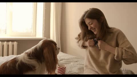Smiling young girl sits on the bed in front of her dog and tries to open a bag of marshmallows