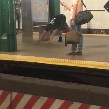 Man in black shirt does yoga stretches in subway station