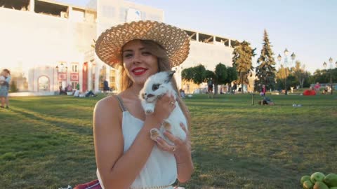 Beautiful young woman on picnic with white rabbit, slow motion