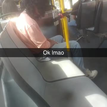 Person pink shirt phone mounted to yellow subway train bus pole
