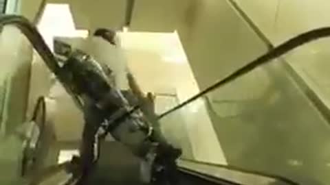 Guy riding bike down escalator second angle