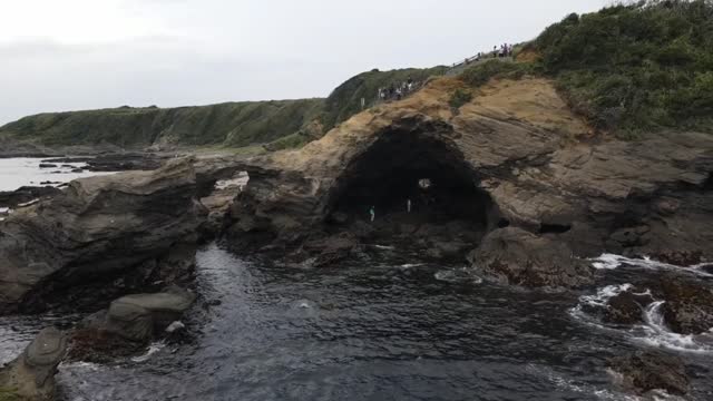 Drone Shot Of People in a Cliffside Cave.