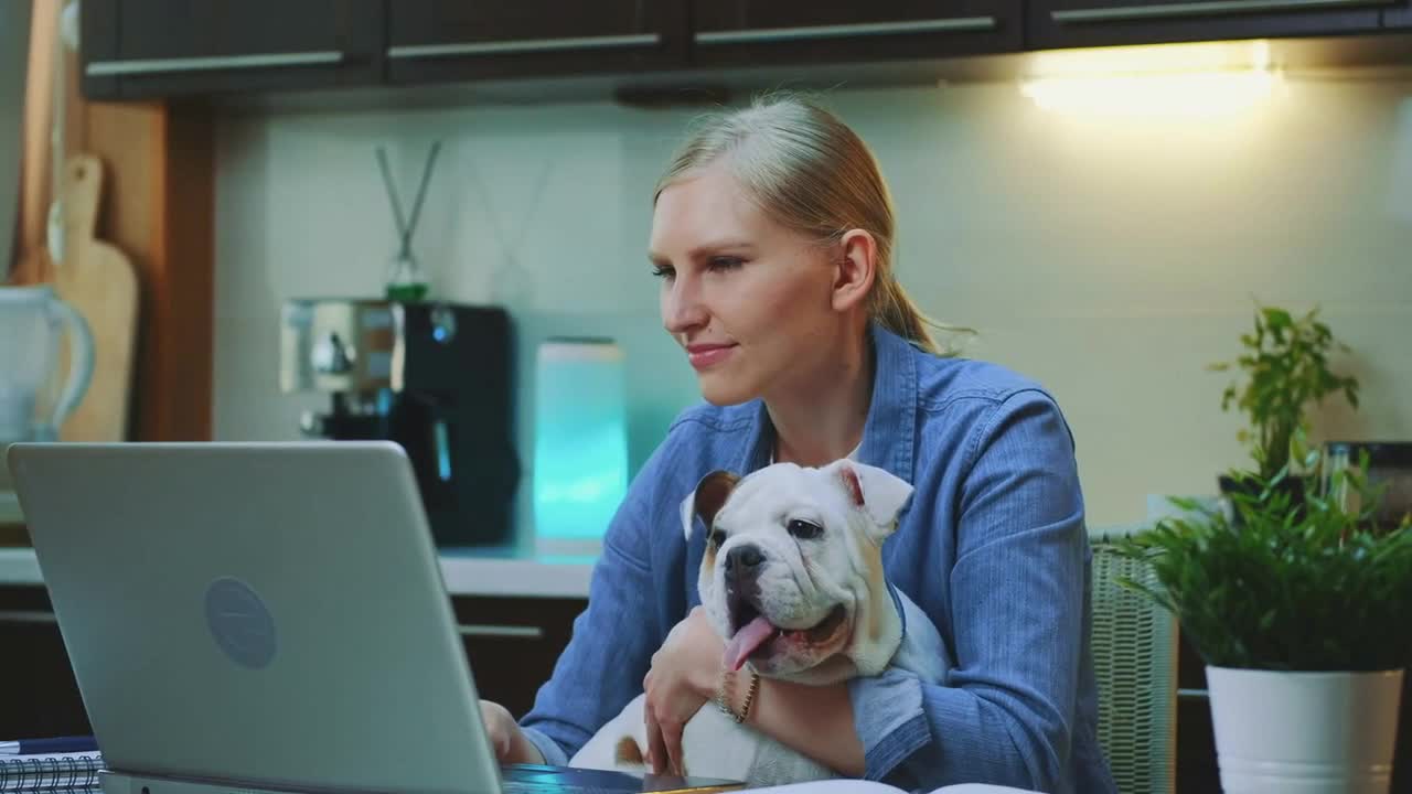 shot of cheerful woman hugging small dog in the kitchen