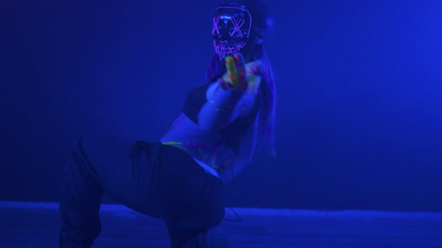 Young woman dancing with a mask under a party light