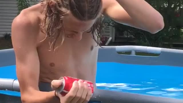 Shirtless long hair kid tries to break can on forehead