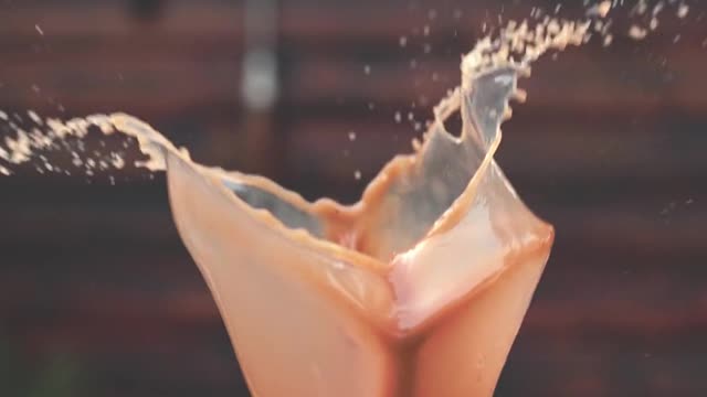 Slow motion shot of coffee with milk flying out of the cup