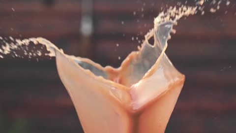 Slow motion shot of coffee with milk flying out of the cup