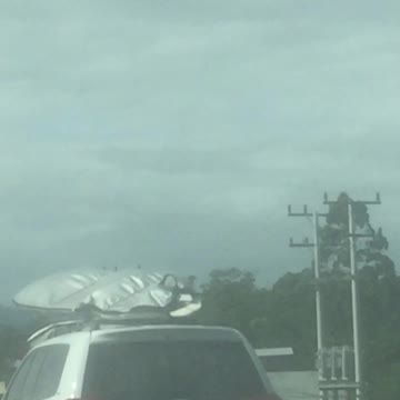 White car with surfboard on top on road