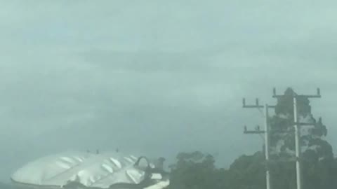 White car with surfboard on top on road
