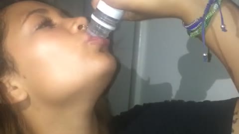 Girl in black holding pepsi downs bottle of vodka