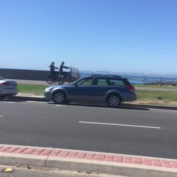 Two guys on wetsuits ride tandem bikes