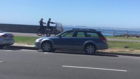 Two guys on wetsuits ride tandem bikes