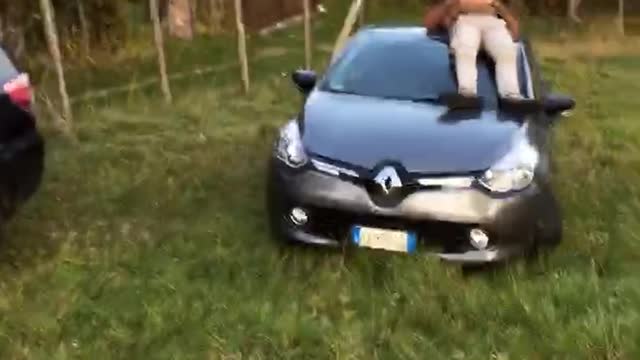 Guy brown jacket laying down on top of car