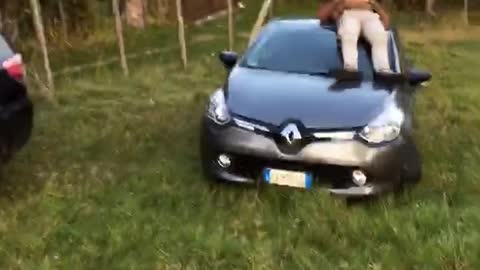 Guy brown jacket laying down on top of car