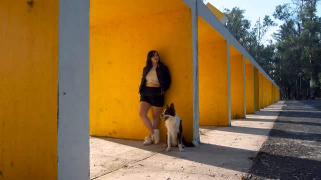 A girl and a dog standing in front of a wall