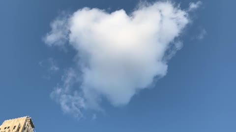 A heart-shaped cloud is floating in the sky.