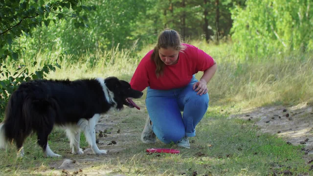 Young plump woman playing with her dog using a plastic disk