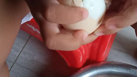 Funny baby busy with eggshell.