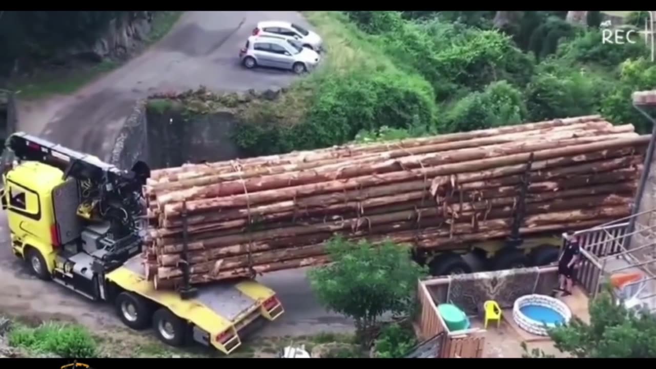 An extra-long trailer loaded with lumber passes through a small bridge.