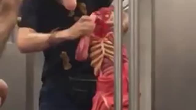 Man in blond wig playing with puppet on train