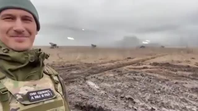 Russian solider smiles in front of rocket attack at Ukrainian positions