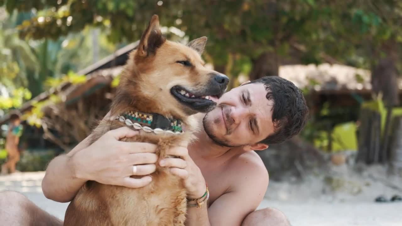 Young guy with his red dog friend at the beach