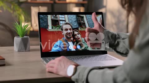 Woman Sitting At Table In Room And Video Chatting With Couple Of Happy Friends On Laptop