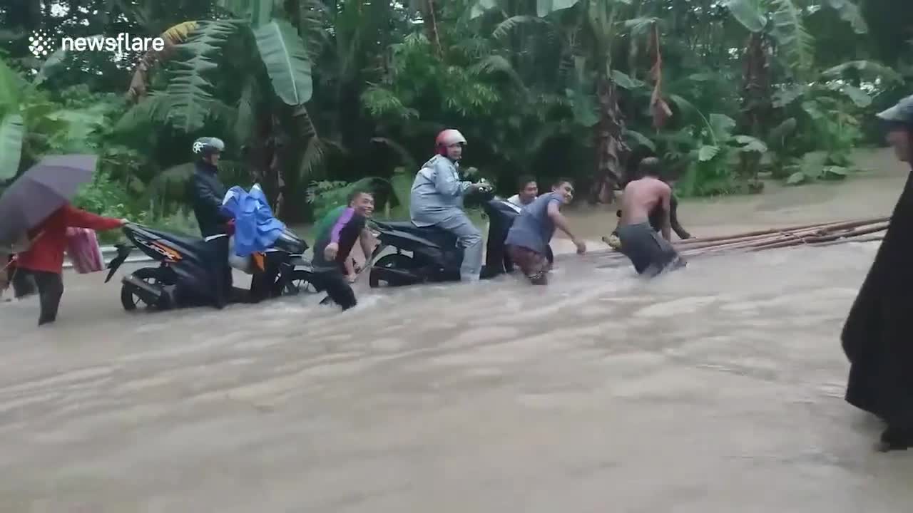 Residents use bamboo raft for motorcycle riders to cross floods