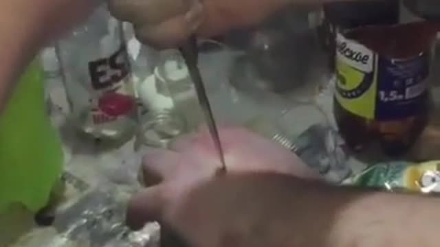 homem perfura a própria mão com a ponta de uma faca