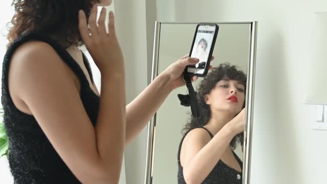 Woman in Black Dress Taking Selfie by the Mirror