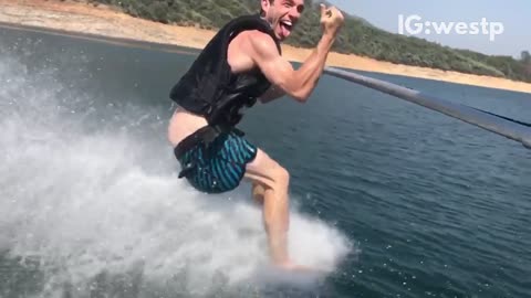 Guy barefoot skiing and his shorts fall down