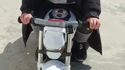 This is a video of a baby riding a toy motorcycle happily.