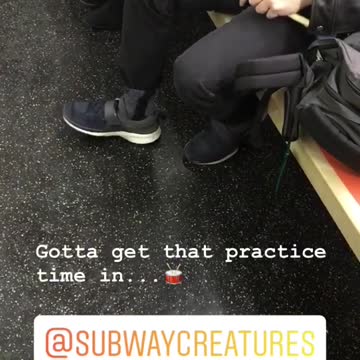 Guy practices the drums with drum pad on lap on subway