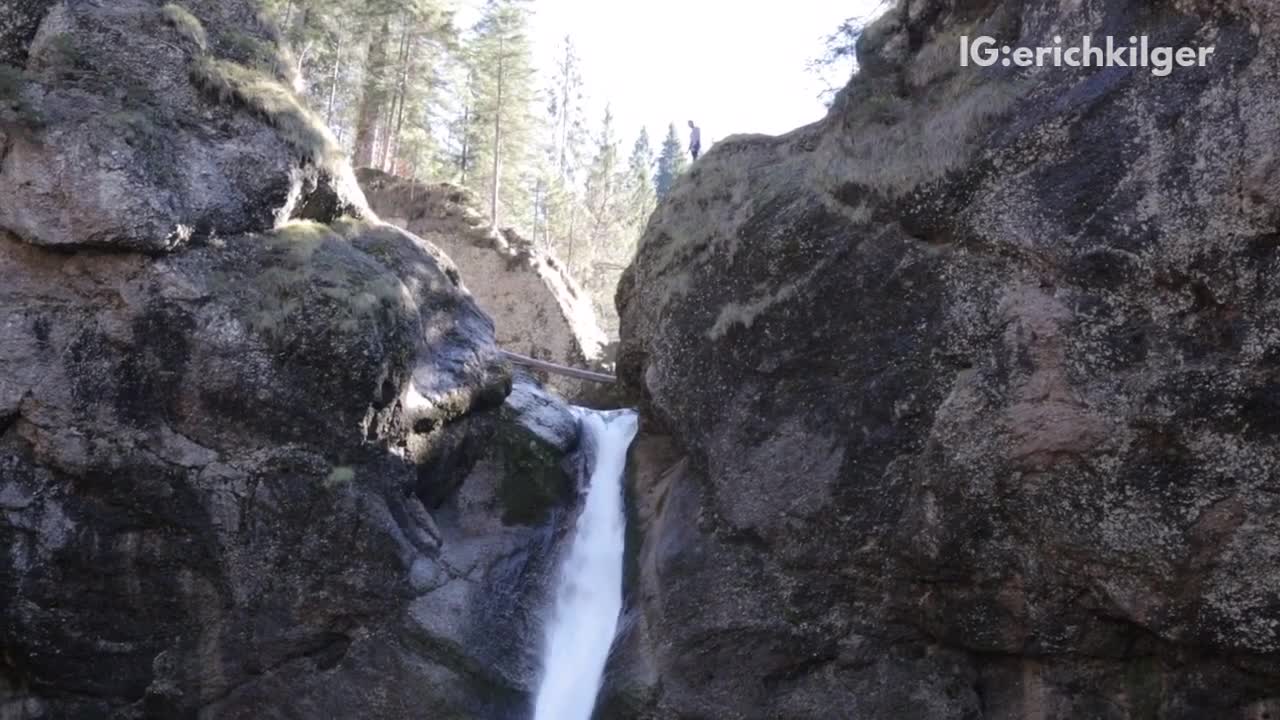 Man in white shirt pants back flips off cliff