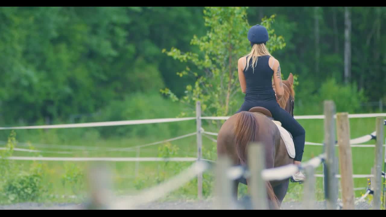 Beautiful young woman riding her arabian horse at farm