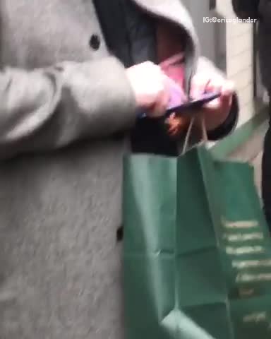 Guy on phone at the subway station, hiding a toy baby doll behind his jacket