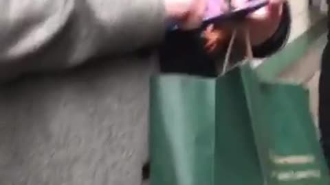 Guy on phone at the subway station, hiding a toy baby doll behind his jacket