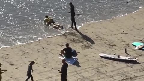 Two men on beach one learns surfing on sand