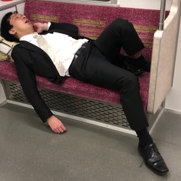 Man in suit asleep on red subway train seat