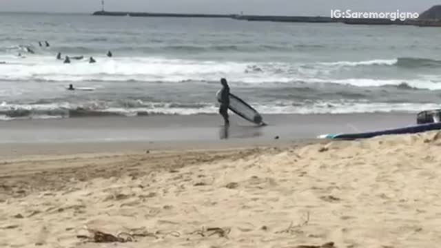 A man dragging a surf board on the beach